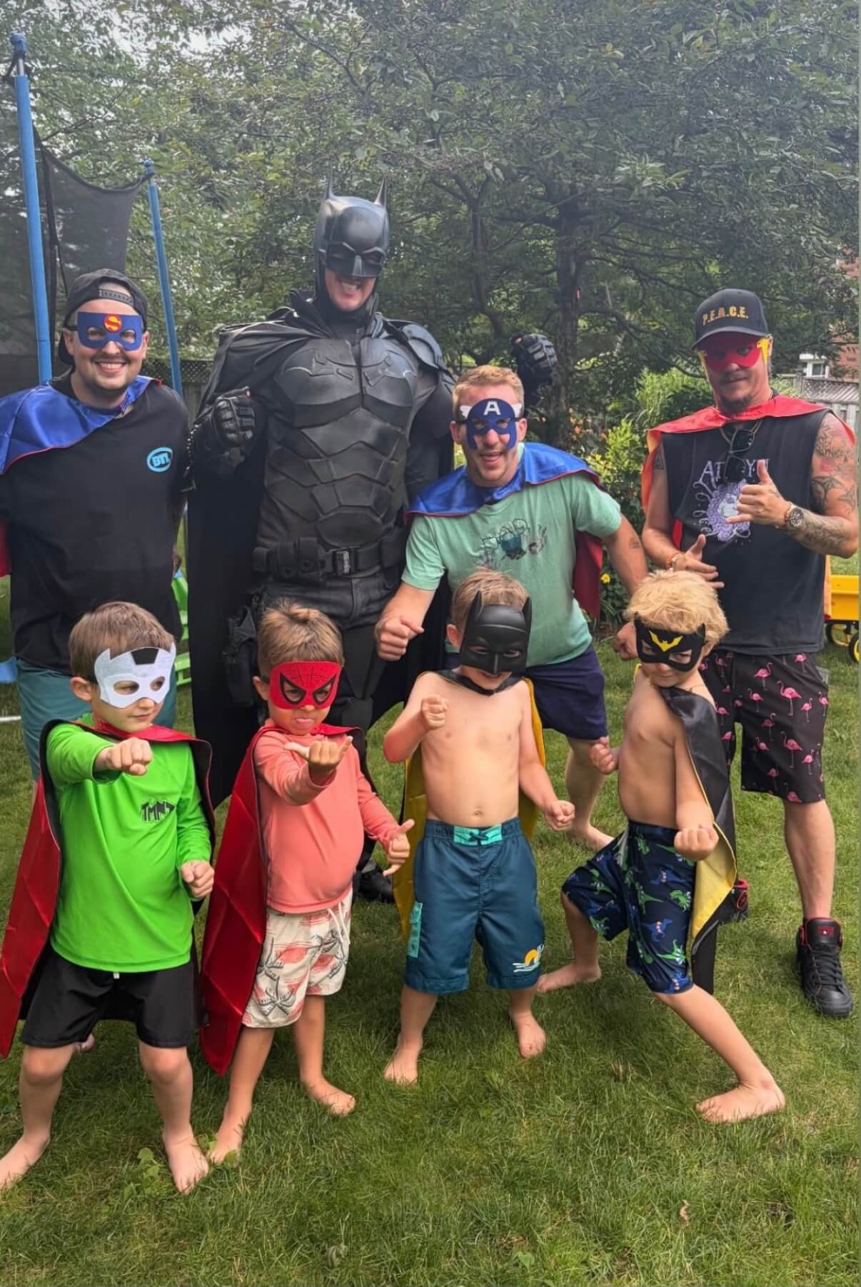 Superhero entertainer posing with a group of children outdoors