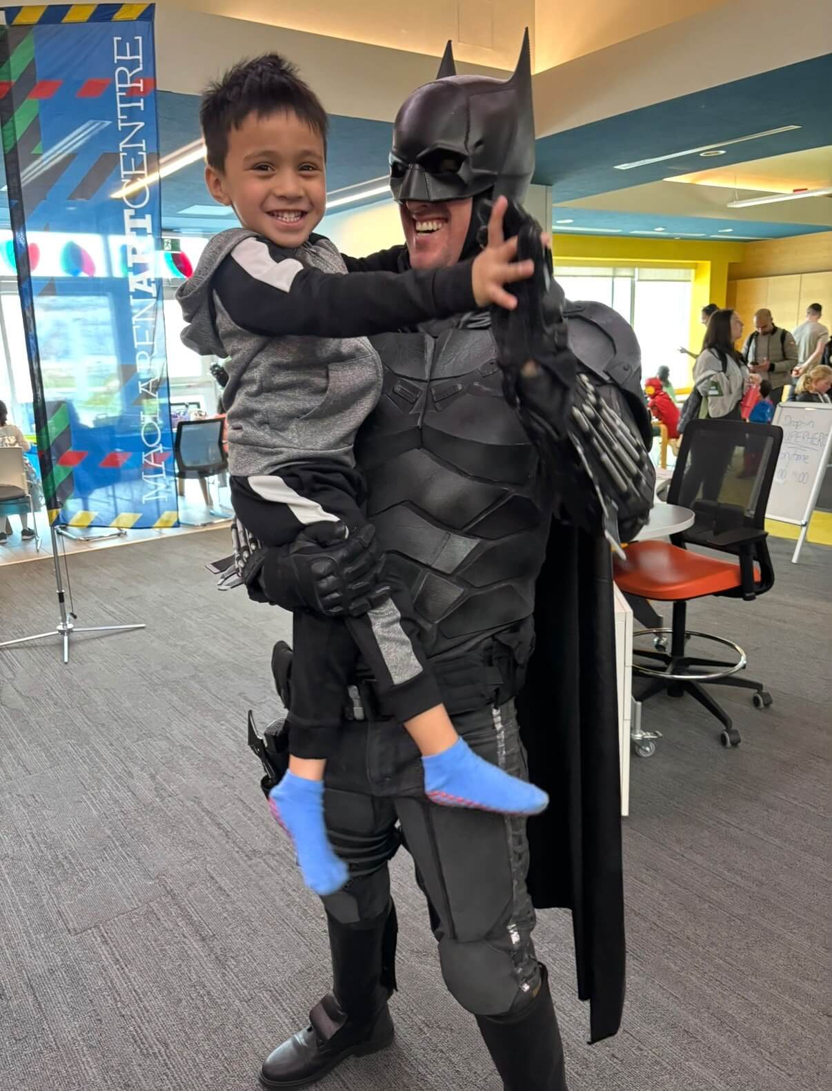 Superhero entertainer holding a smiling child during a family event