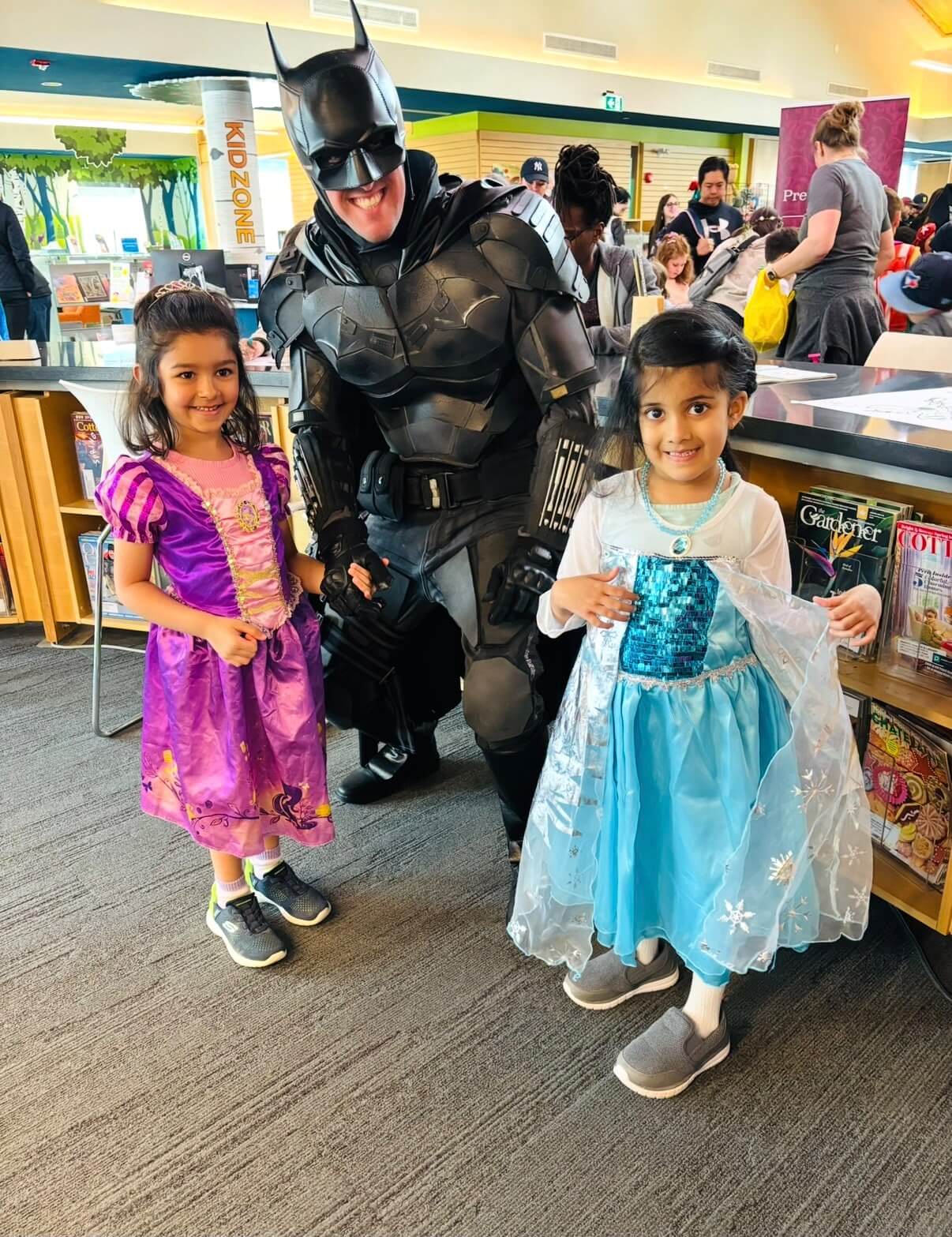 Superhero entertainer posing with children in costumes at a community event