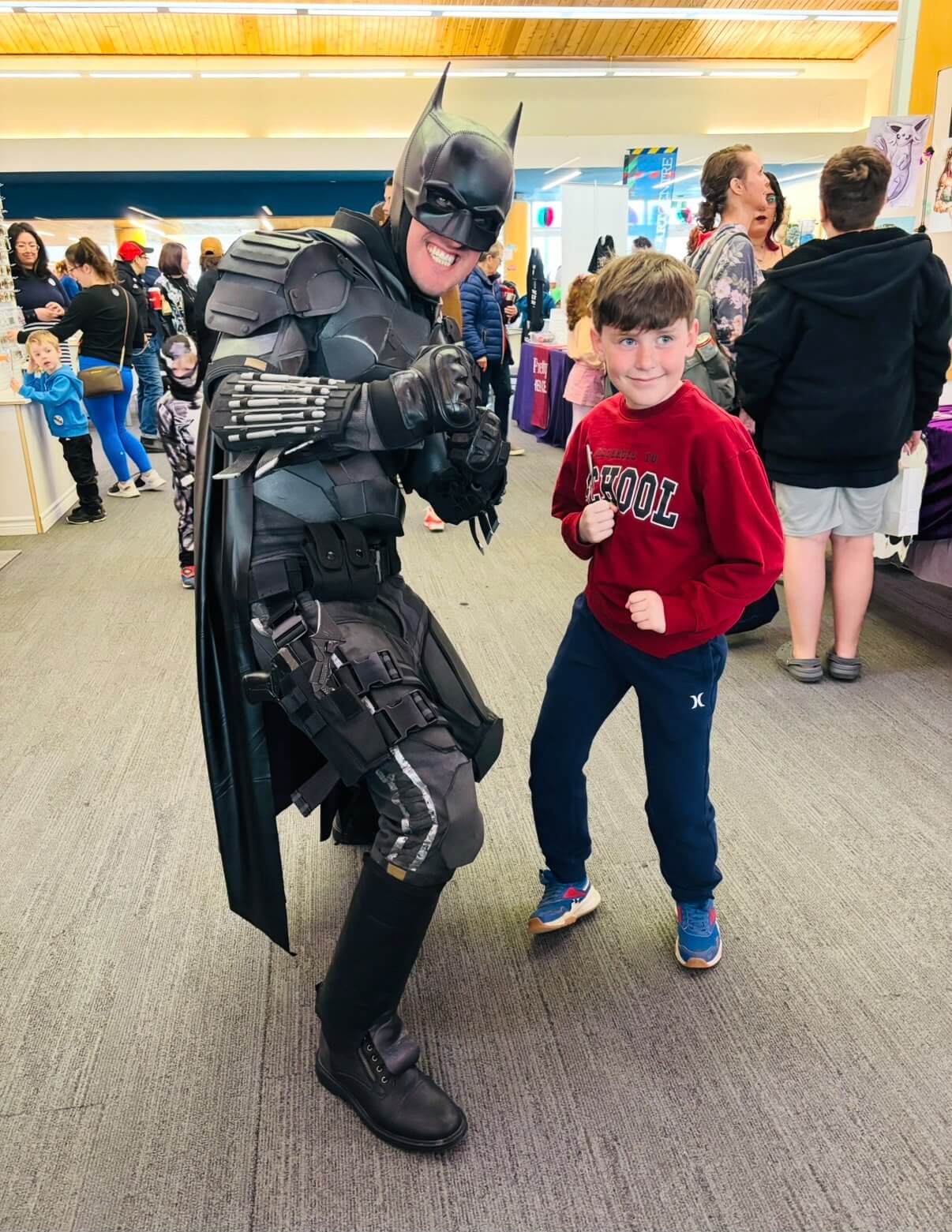 Child and superhero entertainer posing in playful fighting stances